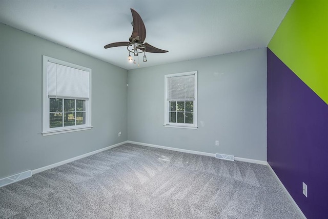 spare room with carpet flooring, baseboards, visible vents, and a wealth of natural light