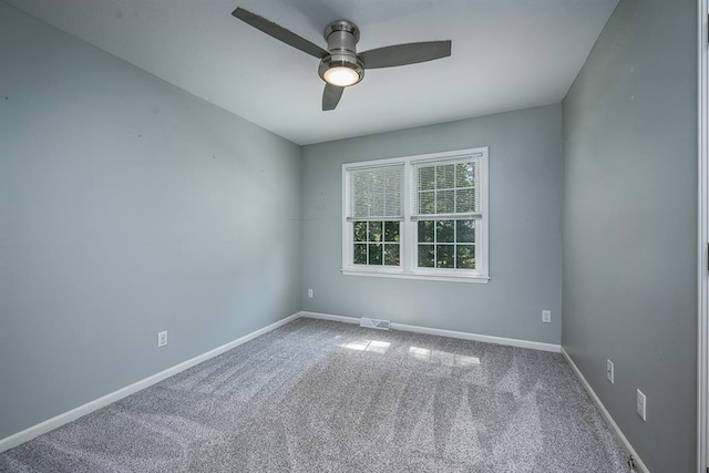 carpeted empty room with visible vents, baseboards, and a ceiling fan