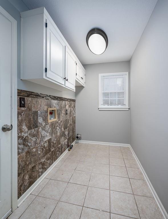 laundry room featuring washer hookup, light tile patterned flooring, cabinet space, and baseboards