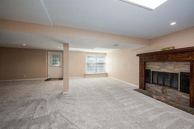 unfurnished living room featuring recessed lighting, baseboards, light colored carpet, and a stone fireplace