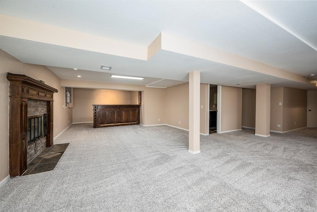 finished below grade area with baseboards, carpet floors, visible vents, and a fireplace