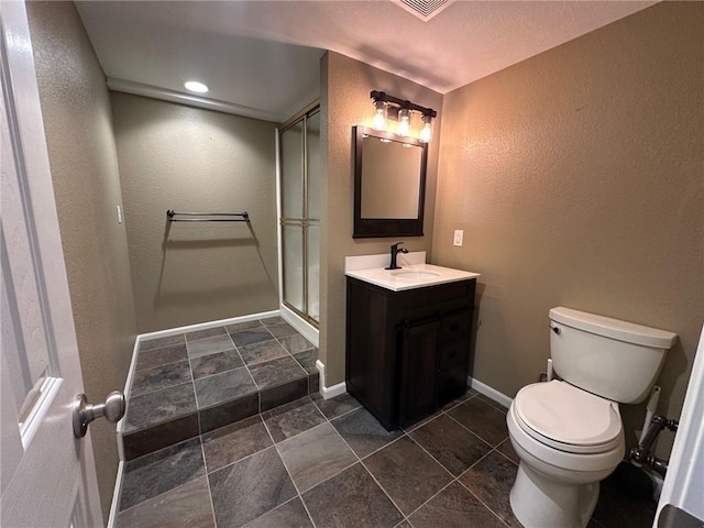 full bath featuring vanity, baseboards, a shower stall, toilet, and a textured wall