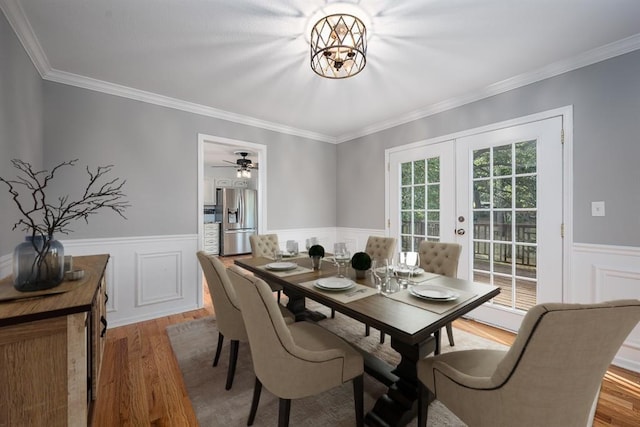 dining room with light wood-style floors, a wainscoted wall, and french doors