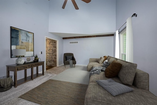 carpeted living area featuring visible vents, ceiling fan, baseboards, and a towering ceiling