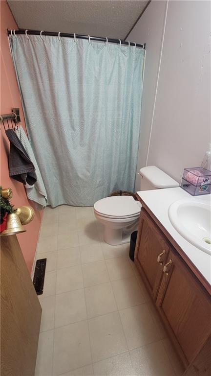 423 Elm St, Mound City, KS 66056 - bathroom with tile patterned flooring, vanity, and toilet