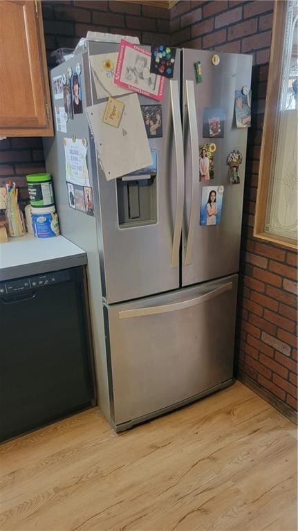 423 Elm St, Mound City, KS 66056 - kitchen with dishwasher, light hardwood / wood-style floors, stainless steel refrigerator with ice dispenser, and brick wall