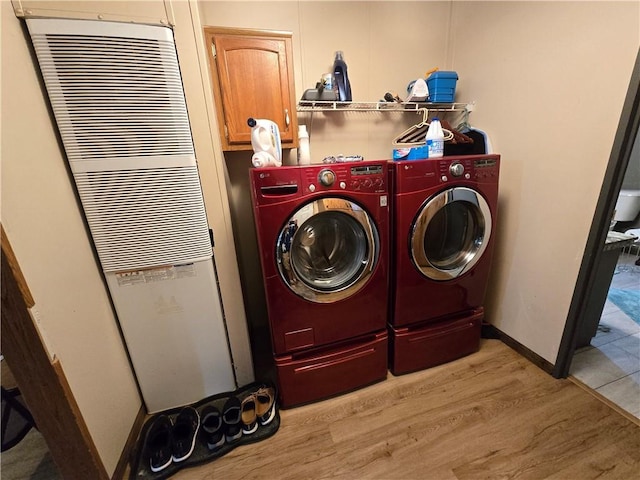 423 Elm St, Mound City, KS 66056 - washroom with light wood-style floors, washing machine and dryer, a heating unit, and cabinet space