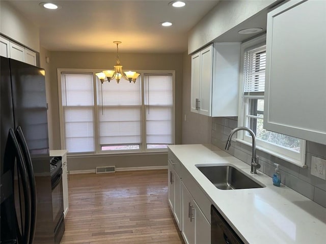 kitchen with black appliances, decorative backsplash, sink, white cabinetry, and decorative light fixtures