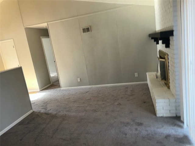 unfurnished living room with a brick fireplace and dark colored carpet