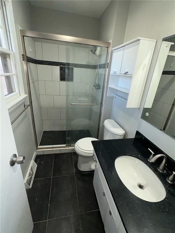 bathroom featuring toilet, an enclosed shower, tile patterned flooring, and vanity