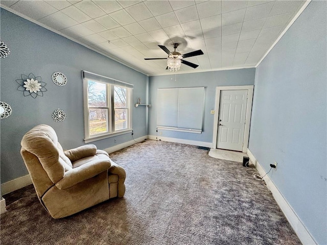 sitting room with ceiling fan, dark carpet, and crown molding