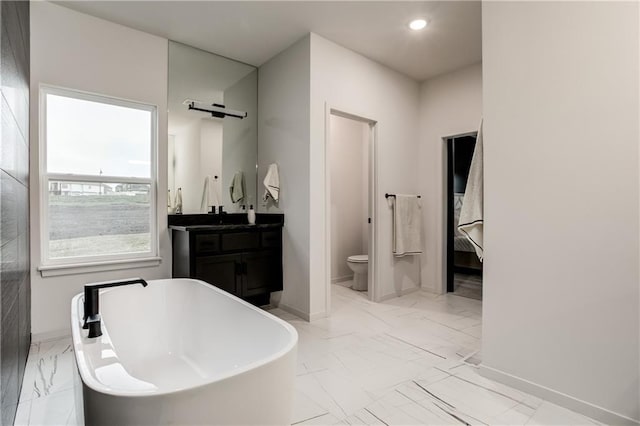 bathroom with vanity, toilet, and a tub