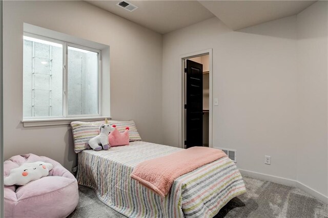 bedroom with a walk in closet and light colored carpet