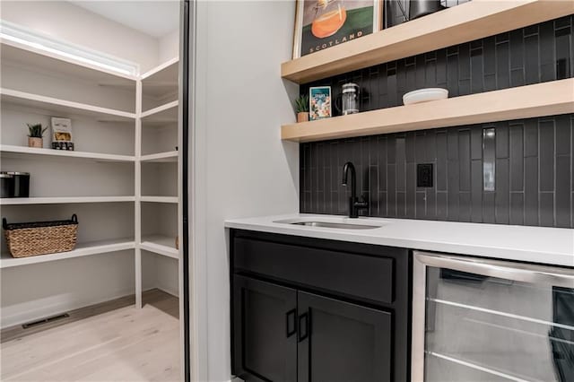 bar featuring wine cooler, sink, and light hardwood / wood-style flooring