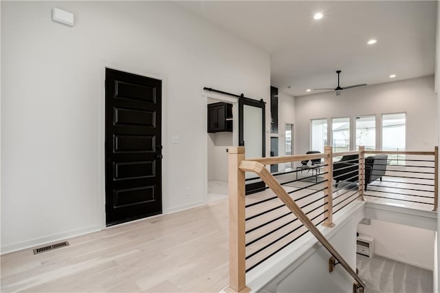 interior space featuring a barn door, ceiling fan, and hardwood / wood-style floors