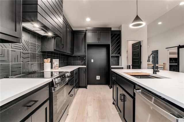 kitchen featuring light wood-type flooring, custom range hood, stainless steel appliances, sink, and pendant lighting