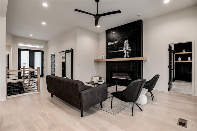 living room with ceiling fan, a fireplace, french doors, and light wood-type flooring