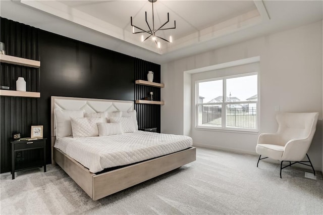 carpeted bedroom with an inviting chandelier and a tray ceiling