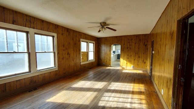 spare room featuring wood walls, a healthy amount of sunlight, and wood-type flooring