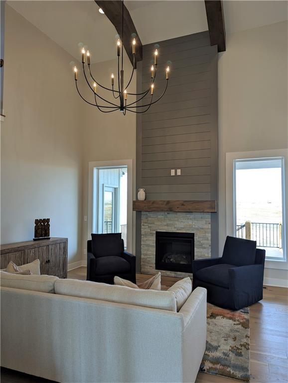 14709 Fairway St, Leawood, KS 66224 - living room featuring a towering ceiling, wood finished floors, a chandelier, a fireplace, and plenty of natural light