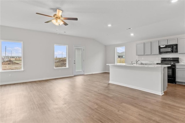 kitchen with light hardwood / wood-style floors, black appliances, gray cabinets, a kitchen island with sink, and ceiling fan