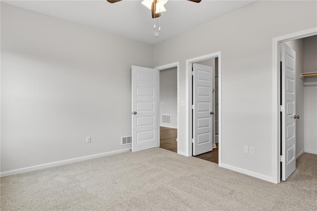 unfurnished bedroom with dark carpet, a closet, ceiling fan, and a spacious closet