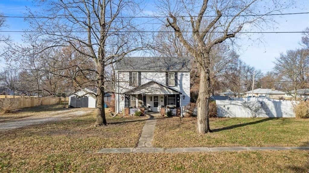 view of front of home with a porch, a storage shed, and a front yard