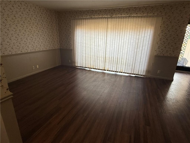 2123 N 8th St, Independence, KS 67301 - empty room featuring wallpapered walls, a wainscoted wall, and dark wood-style floors
