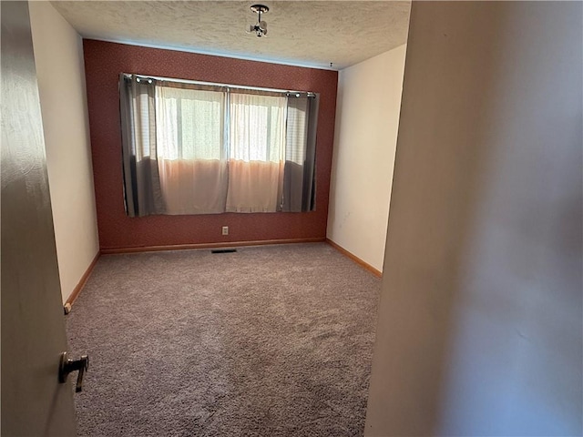 carpeted empty room featuring a textured ceiling