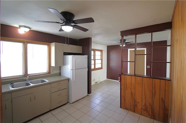 kitchen with light tile patterned floors, white fridge, and sink