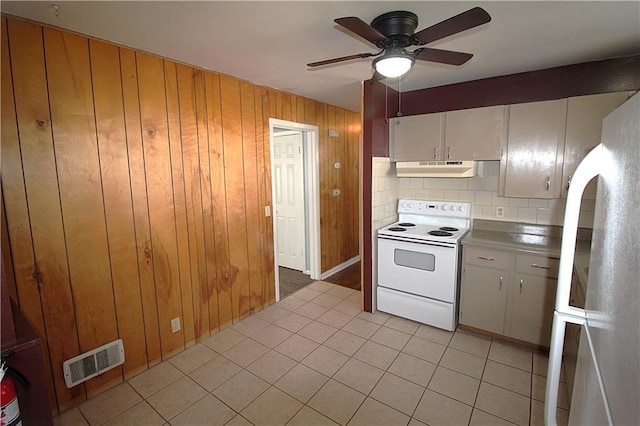 kitchen featuring white appliances, white cabinetry, wooden walls, and backsplash