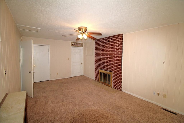 unfurnished living room with ceiling fan, a fireplace, carpet, and a textured ceiling