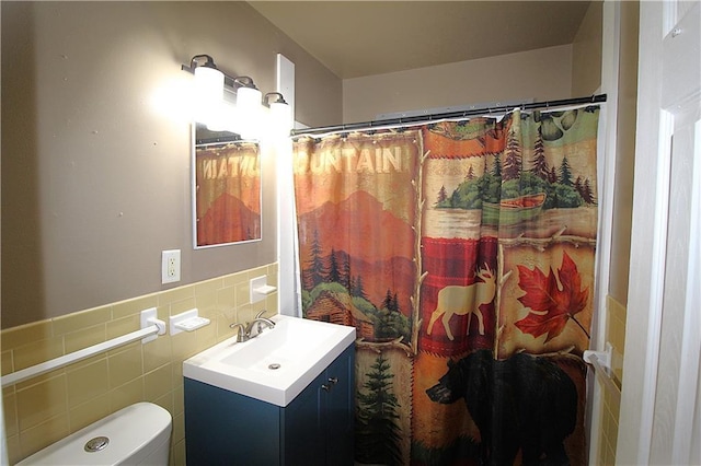 bathroom with a shower with shower curtain, vanity, toilet, and tile walls