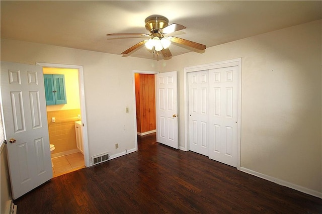 unfurnished bedroom featuring connected bathroom, ceiling fan, dark wood-type flooring, and a baseboard radiator