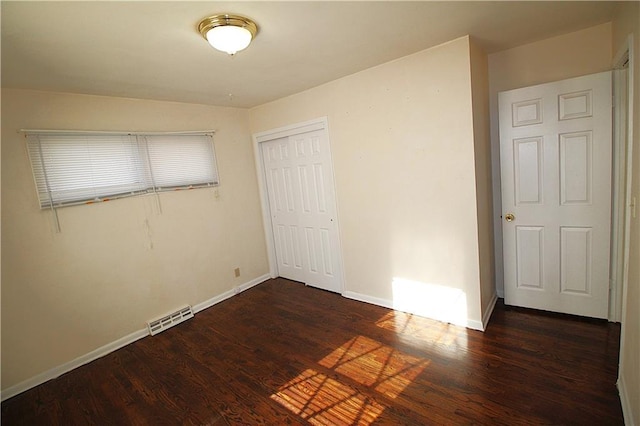 unfurnished bedroom with dark hardwood / wood-style floors and a closet