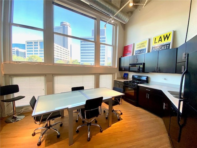 home office featuring light wood-type flooring and a high ceiling