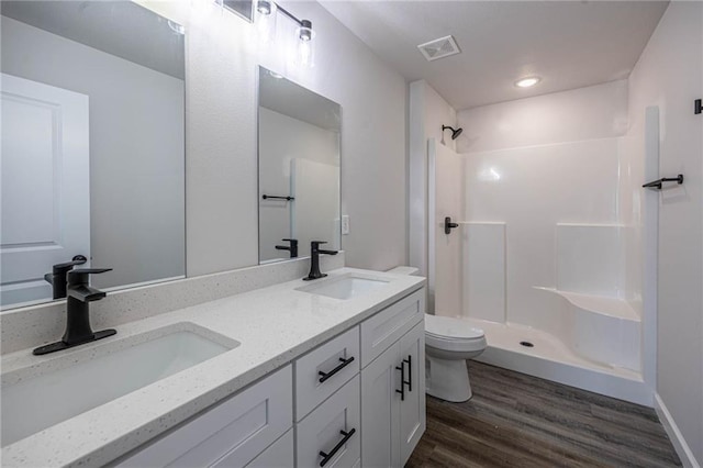 bathroom featuring a shower, hardwood / wood-style floors, vanity, and toilet