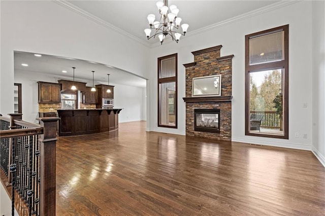 living room with dark hardwood / wood-style floors, a stone fireplace, ornamental molding, and a chandelier