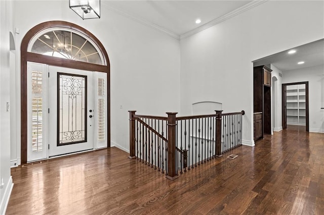 foyer featuring dark hardwood / wood-style flooring, crown molding, and a chandelier