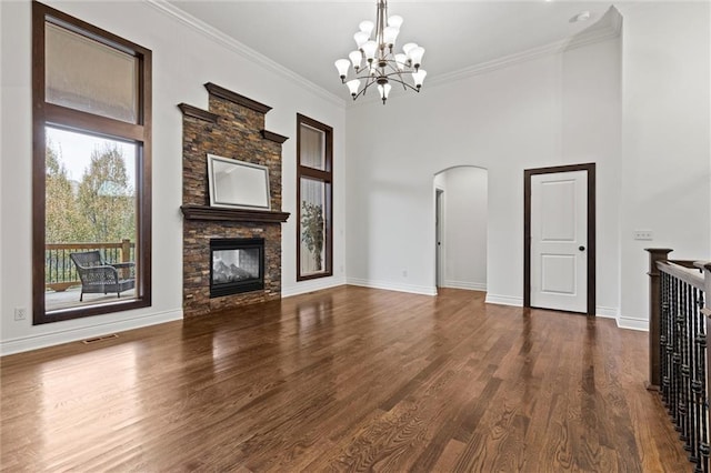 unfurnished living room featuring a stone fireplace, an inviting chandelier, dark wood-type flooring, and ornamental molding