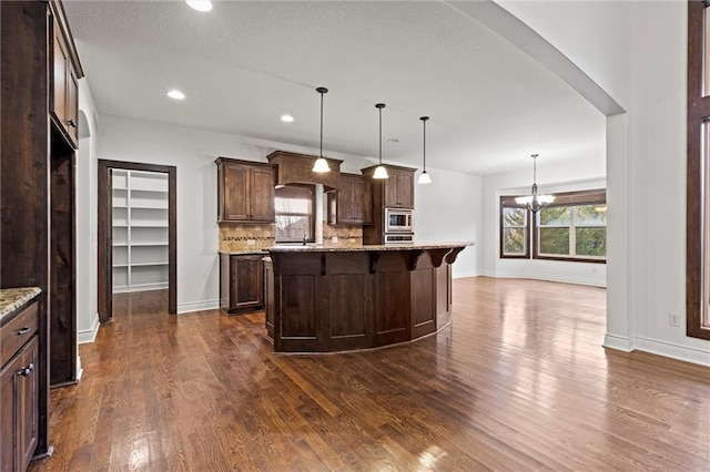 kitchen featuring light stone counters, a center island, stainless steel appliances, and dark hardwood / wood-style floors