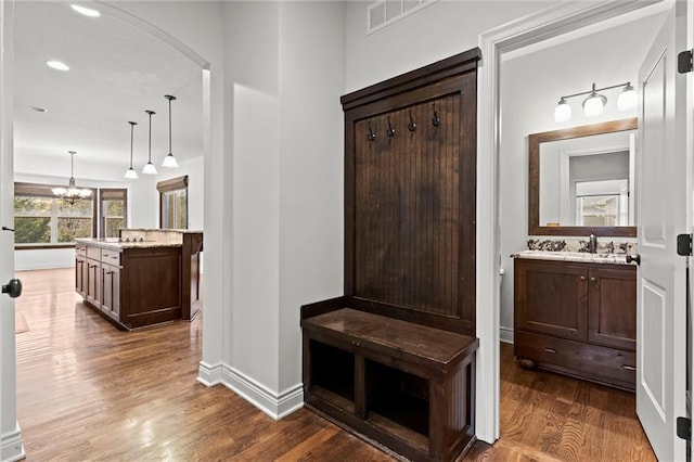 mudroom featuring a notable chandelier, sink, and dark wood-type flooring