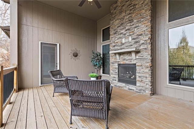 deck with ceiling fan and an outdoor stone fireplace