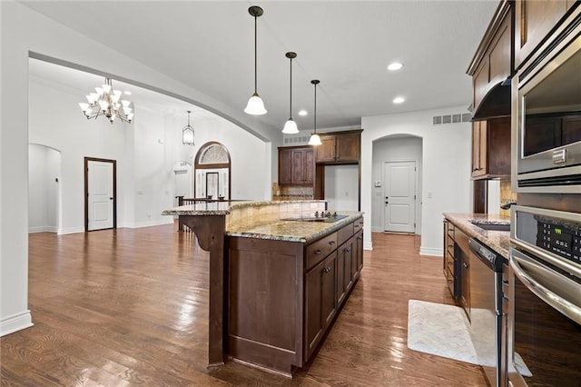 kitchen featuring appliances with stainless steel finishes, dark wood-type flooring, hanging light fixtures, and a notable chandelier