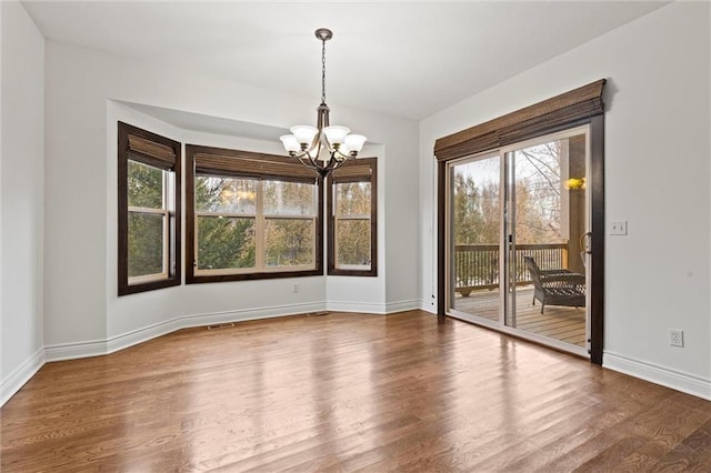 unfurnished dining area with wood-type flooring and a chandelier