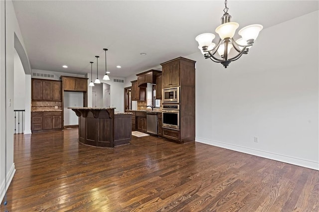 kitchen featuring pendant lighting, backsplash, dark hardwood / wood-style floors, a kitchen island, and stainless steel appliances