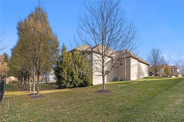 view of side of property with a lawn and central AC