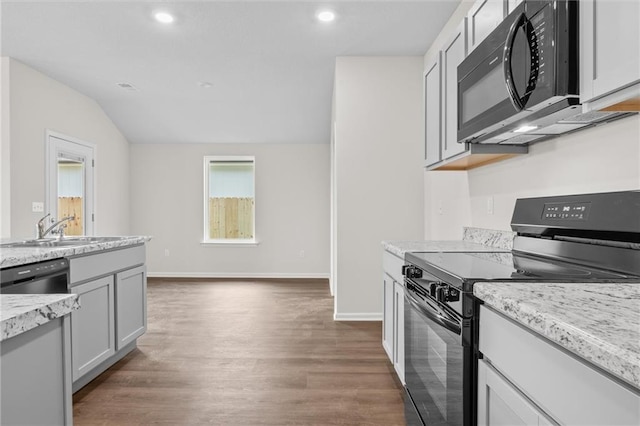 kitchen with black appliances, sink, light stone countertops, dark hardwood / wood-style flooring, and white cabinetry