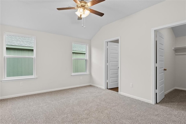 unfurnished bedroom with lofted ceiling, carpet flooring, ceiling fan, a spacious closet, and a closet