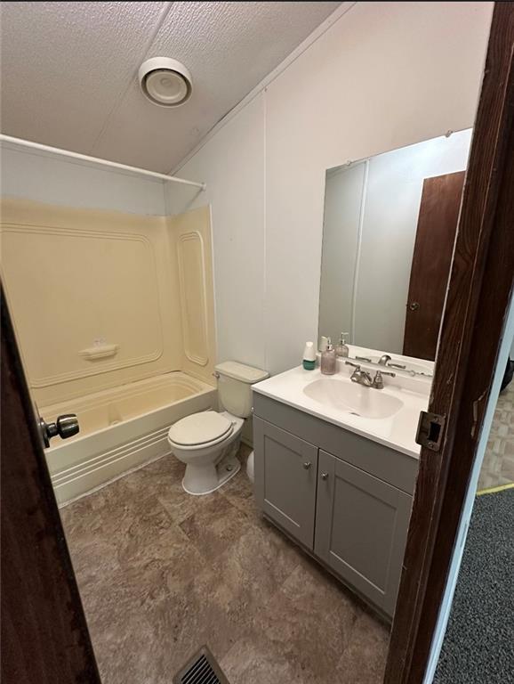 full bathroom featuring vanity, a textured ceiling, toilet, and shower / bath combination